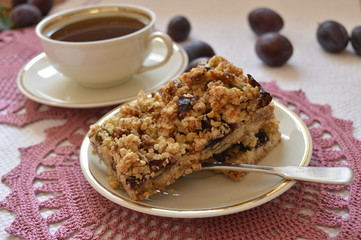 Fototapeta na wymiar  Homemade crumble cake with plums, oatmeal and cup of coffee 