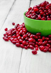 green full plate Cornelian cherries and scattered berry on the white wood board.Selective focus