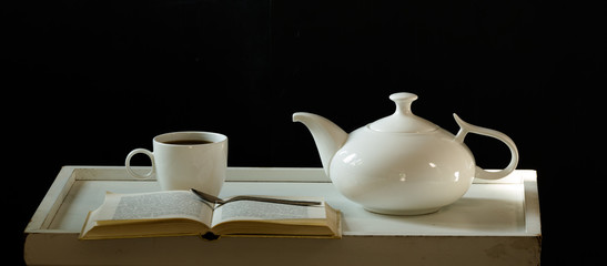 white tea and book on a tray, black background