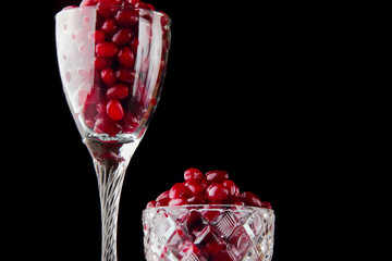 Fototapeta na wymiar fresh cornel berries in glass and vase on black background close-up