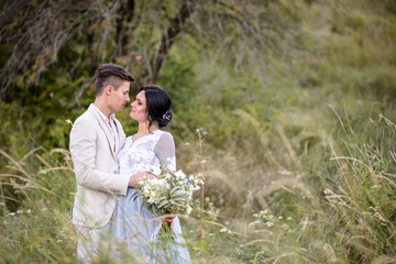 Young couple in love outdoor. Elegant bride and groom posing together outdoors on a wedding day....