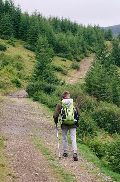 Outdoor portrait of Young man hiking on the mountains,smiling happy portrait of tourist male.extreme sport,sport equipment,travel bag,Caucasian Male hiker walking in forest.