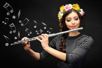 Beautiful young woman with flute. Musical notes design on black background.