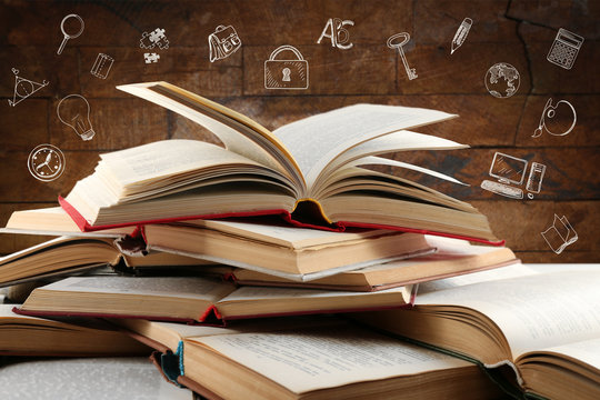 Heap of books with icons on wooden background.