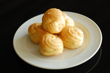 Eclairs or profiterole with chocolate and whipped cream preparing on baking sheet. Spreading chocolate on top of eclair with spoon. Traditional French dessert. Empty space for design text template.