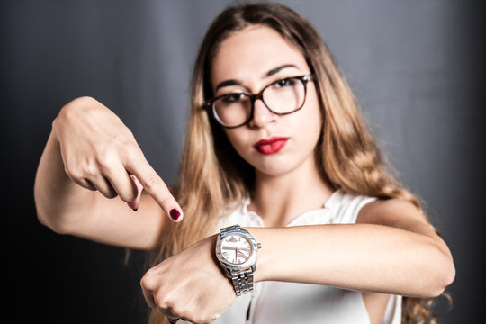 ragazza arrabbiata che indica l'orologio. Concetto della puntualit&agrave;. Fuoco selettivo
