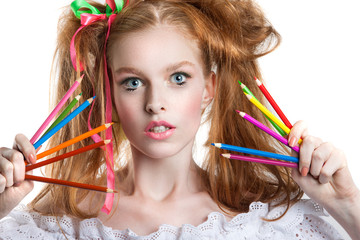 Naklejka premium portrait of a beautiful young girl with colored pencils in hand. Girl with creative hairstyle and makeup holding pencils.