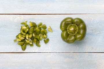Green bell sliced pepper on a blue wooden board, top view