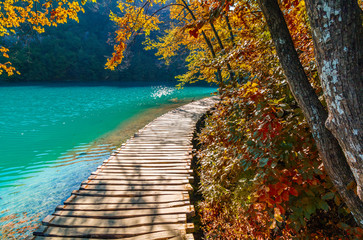 Autumn view of Plitvice Lakes National Park, tourist route on the wooden flooring along the water,...