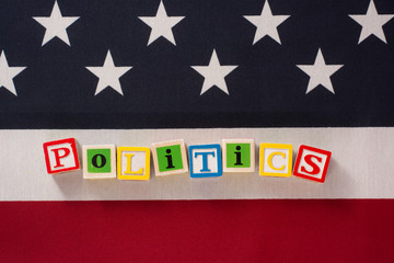 Politics in America!  The word politics spelled out in letter blocks on top of an American flag.  