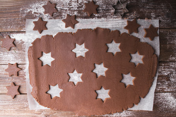 Baking Christmas cookies.  Roll out the dough to cut out stars on a wooden background