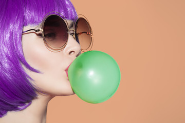 Pop art woman portrait wearing purple wig. Blow a blue bubble ch