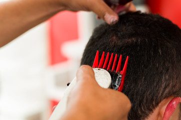 Close up of red machine cutting a man hair, short hair