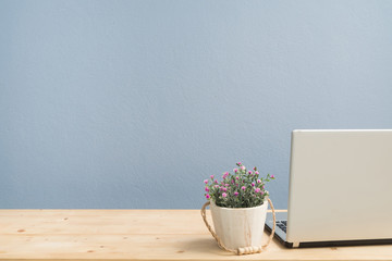 Office Desk with pink rose on flower pot and back monitor laptop.
