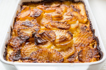 baked potatoes with cheese on baking sheet white bowl.
