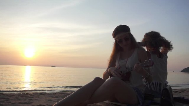 Hippie Girls Having Rest Sitting on a Sand on the Beach at Sunset. Slow Motion