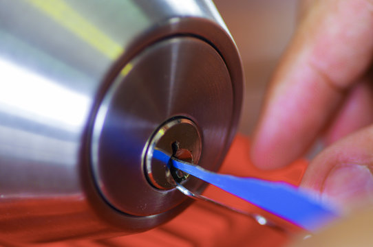 Closeup hands of locksmith using metal pick tools to open locked door