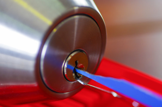 Closeup hands of locksmith using metal pick tools to open locked door