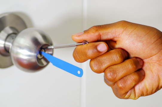 Closeup hands of locksmith using pick tools to open locked door