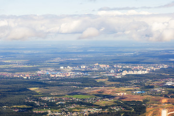 Fototapeta premium Small town near the forest in Russia. Aerial view of thick clouds and their shadows over the land, the landscape. 