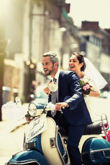 Newlyweds having fun on a decorated vintage scooter