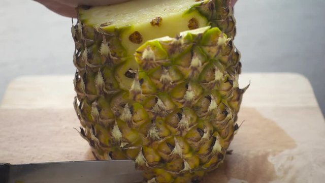 Cutting Juicy Ripe Pineapple with a Knife on a Wooden Board. Slow Motion