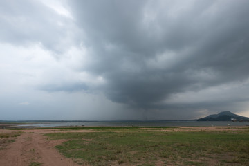 Grass land with storm rain cloud over the lake.