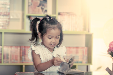 Child read, cute little girl reading a book in the library