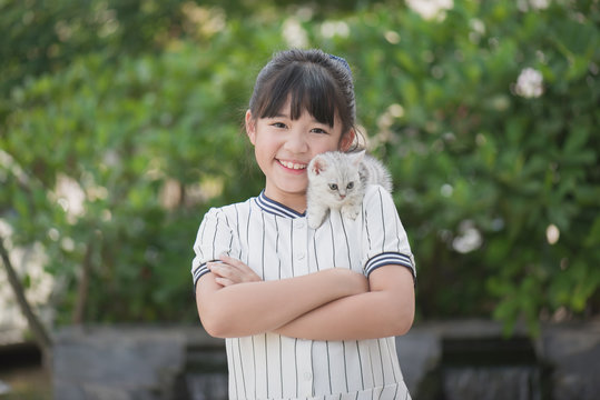 Beautiful Asian girl holding Lovely  kitten with sunshine in the park