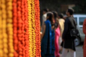 Marigold flowers garland background with people in the background 

