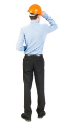 Backview of an engineer in construction helmet stands. Standing young guy. Rear view people collection.  backside view of person.  Isolated over white background. The man in trousers and shirt