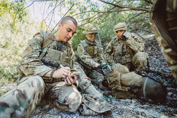 British special forces soldiers with weapon and officer holds a radio station, and give orders subdivision. war, army, technology and people concept.