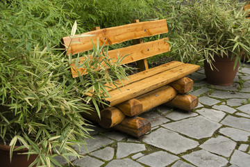 Wooden park bench with a flower pot bamboo.