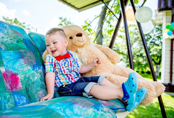 little boy sits in a garden swing