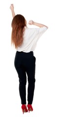 Back view of  joyful woman celebrating victory hands up. Rear view people collection. backside view of person. Isolated over white background. slender redhead in a jeans shows symbol of success or