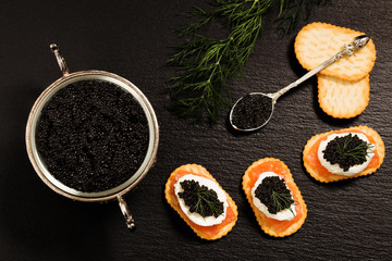 Black caviar served on crackers with salmon and cream cheese.