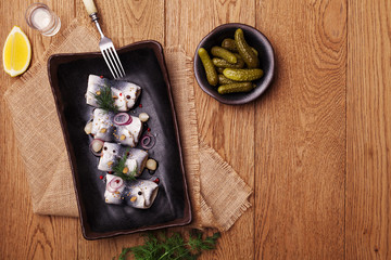 Fototapeta na wymiar Rolled herring in vinegar, served with onions and pickles.