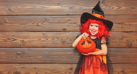 funny child girl in witch costume  for Halloween with pumpkin Ja