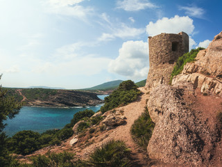 Fototapeta na wymiar Torre del Porticciolo - Ruins of Ancient Watchtower (Nuraghe) on the Hill over the Porticciolo Beach near Alghero, Sardinia, Italy