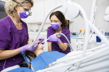 Mature Dentists Working On Patient's Teeth