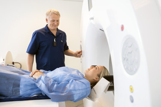 Professional Looking At Female Patient Undergoing CT Scan