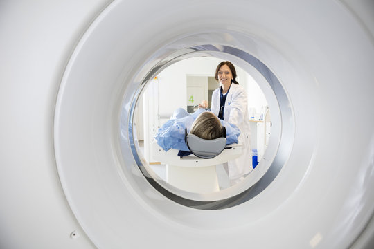 Doctor Looking At Patient Undergoing CT Scan
