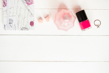Paper for notes, perfume, ring, nail polish, notebook on white wooden background. Casual blogger home office. Social network content.