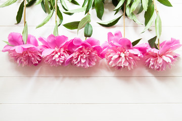 Bright pink peonies on white wooden background. Fresh summer floral background with copy space. Top view, flat lay