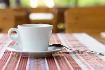 Photo of white cup of coffee on a traditional restaurant table in Moldova, tablecloth with ornaments, shallow focus