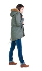 Naklejka premium back view of standing young beautiful brunette woman in park. girl in warm jacket watching. Rear view people collection. backside view of person. Isolated over white background.