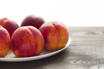 Fresh juicy nectarines in a white plate.