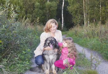 Obraz na płótnie Canvas Женщина с дочкой и собакой на прогулке в парке