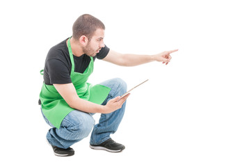 Supermarket young employee pointing something holding tablet
