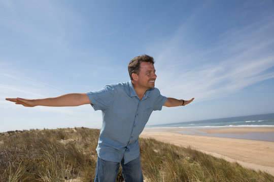 Man on beach arms up, vacation concept of freedom